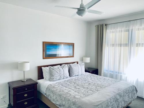 阿德莱德大西洋西海滩公寓的白色卧室配有床和吊扇