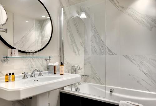 巴黎圣母海岸酒店的一间带水槽、浴缸和镜子的浴室