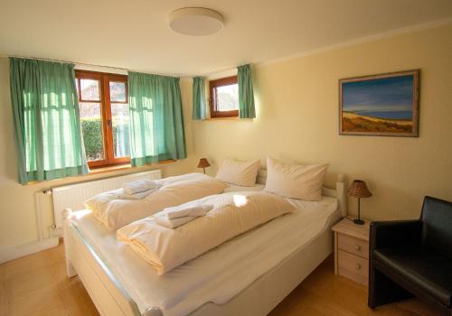 内贝尔Inselhotel Kapitän Tadsen / Amrum的卧室设有一张大白色的床铺,设有窗户