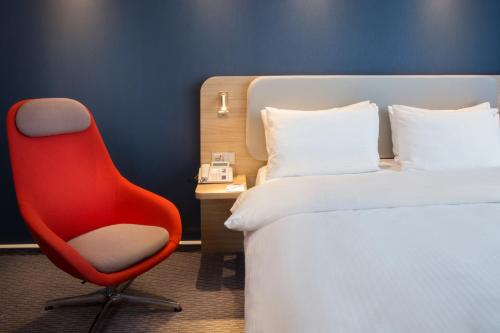 巴登-巴登巴登 - 巴登快捷假日酒店的一张红色椅子坐在房间床边