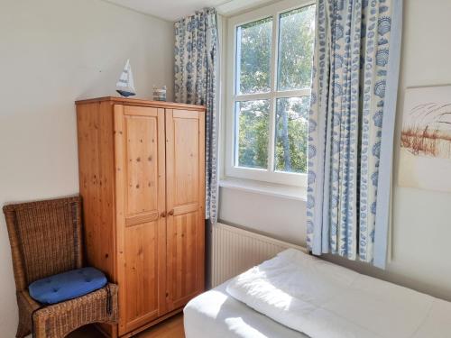 栋堡Prachtig vakantiehuis in Domburg DO38的一间卧室设有一张床、一个窗口和一把椅子