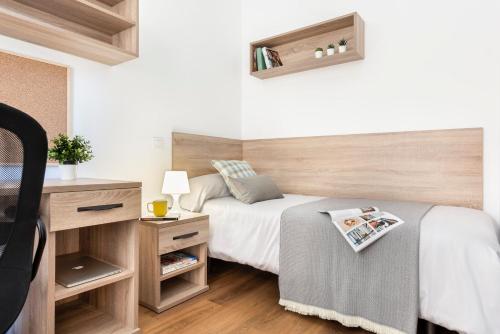 塞维利亚Micampus Armendariz Student Residence的一间卧室配有一张带木制床头板的床