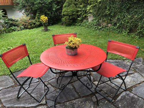 莱茵费尔登Dreiländereck, schöne Ferienwohnung mit großem Freisitz的一张红色桌子,上面有三把椅子和盆栽植物
