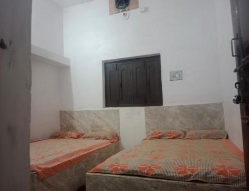 DongargarhIndian Family Lodge, Rajnandgaon, Chhattisgarh的卧室配有两张床,墙上设有橱柜。