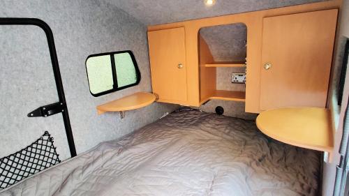 霍克斯黑德Darwin Teardrop Caravan for Hire from ElectricExplorers的小房间设有床和镜子