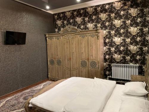 KogonTURKISTAN Hotel的一间卧室设有一张大床和一个木制床头板