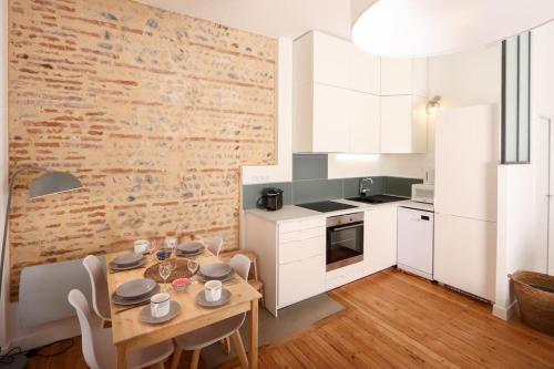 图卢兹Confortable T2 à Saint Aubin的厨房配有木桌和砖墙