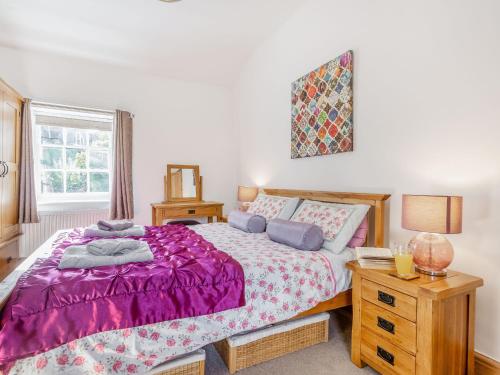 多尔盖罗Bro Dawel的一间卧室配有一张带紫色棉被的床