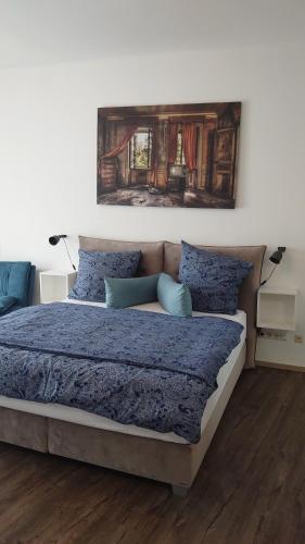 美因茨Maxim Apartments Mainz的一间卧室配有一张带蓝色床单的床和墙上的绘画。