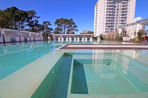 埃斯特角城Yoo Punta Del Este的一座拥有蓝色和绿色水的大型游泳池