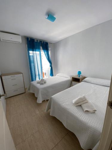 滨海罗克塔斯Apartamento Aguadulce Playa的酒店客房设有两张床和窗户。