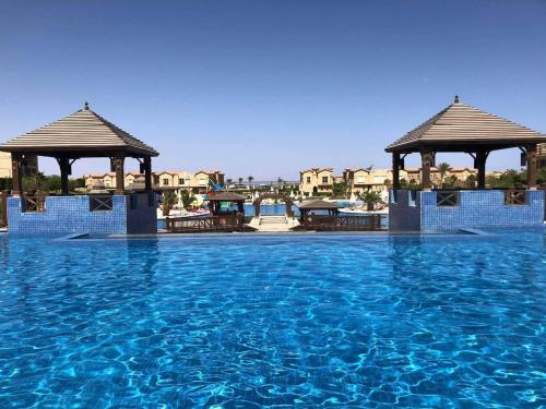 艾因苏赫纳Villa at Piacera Resort-seaview的一个带两个凉亭和蓝色海水的游泳池