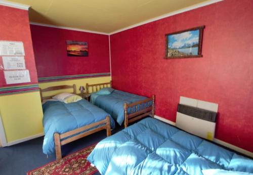 蓬塔阿雷纳斯Hospedaje Independencia y camping的红色墙壁客房的两张床