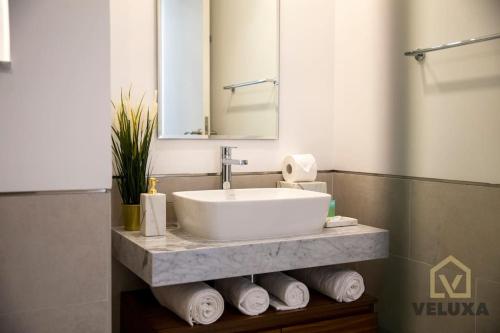 迪拜Veluxa - Luxury and bright 1 bedroom apartment, Burj view!的浴室设有水槽和一堆毛巾