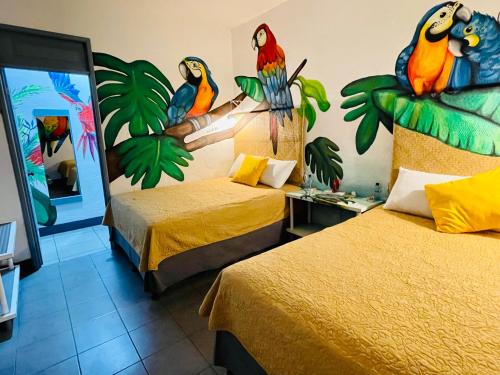 危地马拉安地瓜Hotel y Arte Antigua by Amazing Guatemala Travel的一间设有两张床的房间,墙上有鸟儿