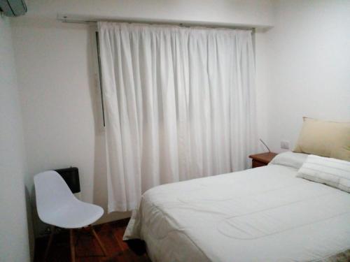罗萨里奥Lourdes的卧室配有白色的床和白色椅子