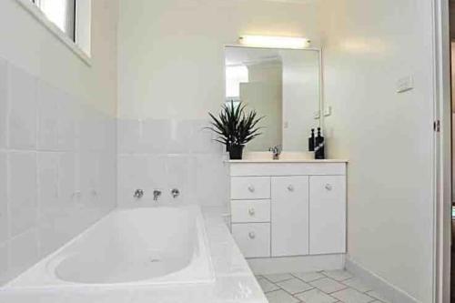 科夫斯港Beachfront Retreat - Ducted Air - Free Wifi的白色的浴室设有浴缸和大镜子