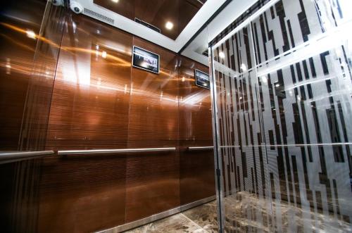 阿特劳阿迪吉尔住宅酒店的淋浴间设有木墙和玻璃门