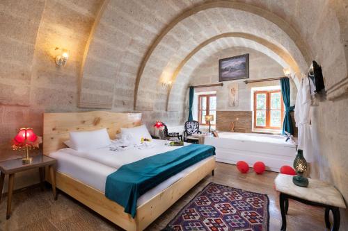 阿瓦诺斯HacıAşık Konağı Butik Hotel的一间卧室设有一张大床和一个浴缸