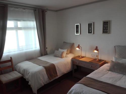 开普敦The Quadrant, G505的一间卧室设有两张床、一个窗口和两盏灯。