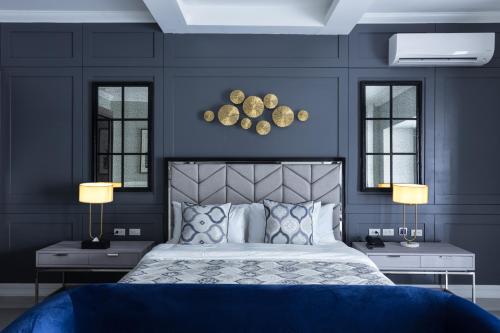 巴科洛德Stonehill Suites的一间卧室设有蓝色的墙壁和一张带两盏灯的床。