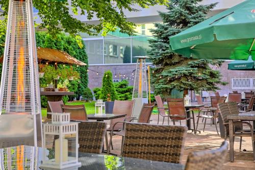 华沙格罗马达华沙中心酒店的庭院配有桌椅和遮阳伞。