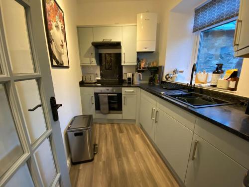 因纳利森The Wee Bunk House - Innerleithen的厨房铺有木地板,配有白色橱柜。