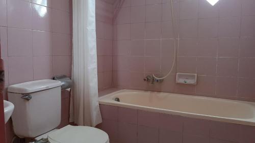 ParepareHotel Parewisata的粉红色的浴室设有卫生间和浴缸。