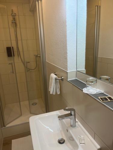 BremenGasthof Wulf的浴室配有盥洗盆和带镜子的淋浴