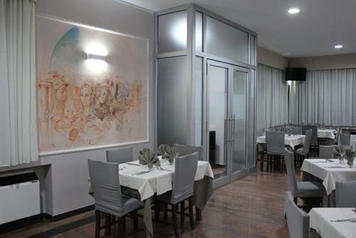 TrevicoPrestige的一间用餐室,配有白色的桌椅和绘画作品