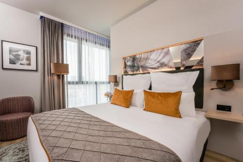 巴塞罗那Leonardo Royal Hotel Barcelona Fira的酒店客房带一张大床和一把椅子