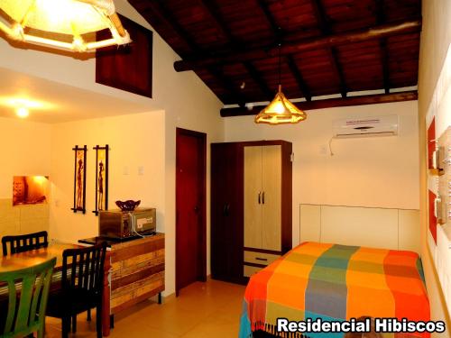 加罗帕巴Residencial Hibiscos - Vista Mar的一间卧室配有一张床铺和一张桌子,还设有一间厨房