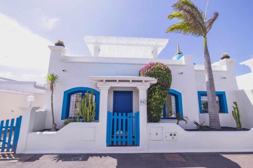 科拉雷侯Villa Tiguaro Piscina Climat Jacuzzy AC Villa 9 12的白色的房子,有蓝色的门和棕榈树
