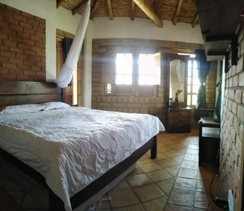 SutamarchánHermoso lugar familiar cerca a Villa de Leyva的一间卧室设有一张床和砖墙