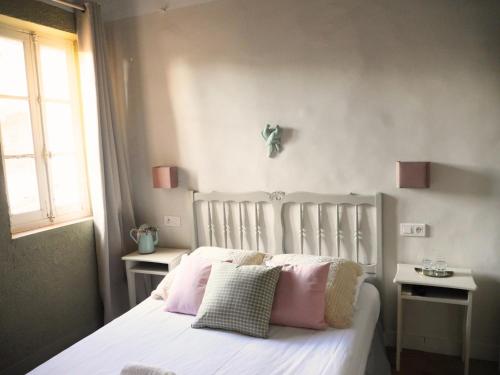 屈屈龙la dame jeanne的卧室配有白色床和粉红色枕头