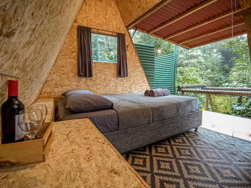 米卡ECO Cabin - TANOA Minca的一间卧室配有一张床和一张桌子及一瓶葡萄酒