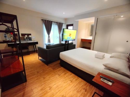 马尼拉The Hub District Garden Suites的酒店客房配有一张床、一把椅子和一台电视。