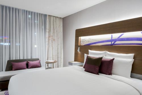水原市水原安巴萨多尔酒店的卧室配有一张带紫色枕头的大型白色床。
