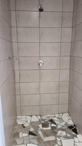 eNyalunguThe Unit Party House的带淋浴的浴室,铺有瓷砖地板。