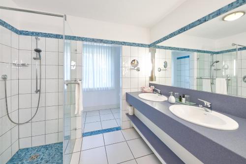 贝尔恩卡斯特尔-库斯Wein- und Landhaus S A Prüm的一间带两个盥洗盆和淋浴的浴室