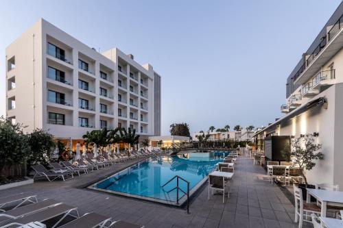 帕福斯阿内密套房公寓式酒店的一座带游泳池和椅子的酒店和一座建筑
