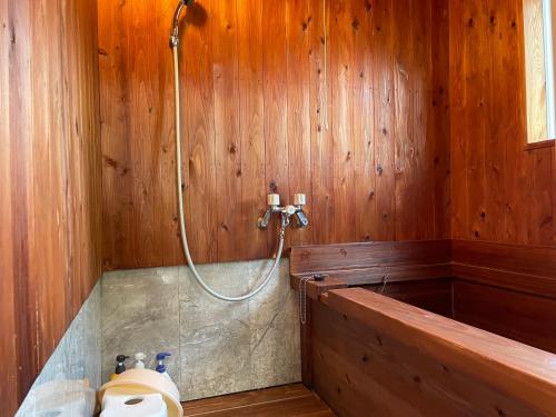 由布市旅館 竹屋 Takeya的木制墙壁上带淋浴的浴室