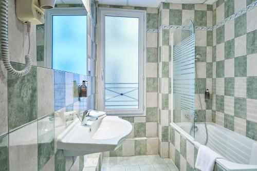 巴黎Hôtel Kabanel by Happyculture的一间带水槽和浴缸的浴室以及窗户。
