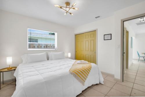 劳德代尔堡LoKal Rental Tropical Florida destination的白色的卧室设有白色的床和黄色的门