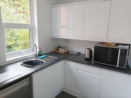 利物浦Victorian Renovation Room 5的厨房配有白色橱柜、微波炉和水槽。