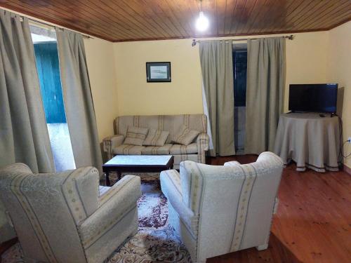 锡列达Casas de Maragouzos的客厅配有两把椅子、一张沙发和一张桌子