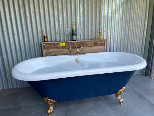 布里斯托The Shepherd’s Nest的浴室设有蓝色浴缸,提供两瓶葡萄酒