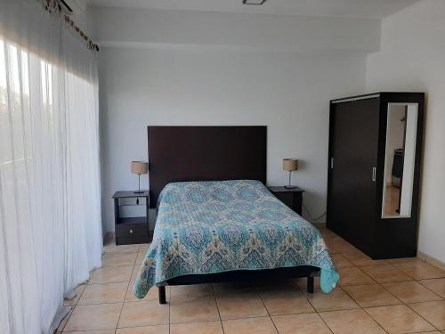 蒂格雷Hermoso departamento en complejo residencial的一间卧室配有一张带蓝色毯子和镜子的床