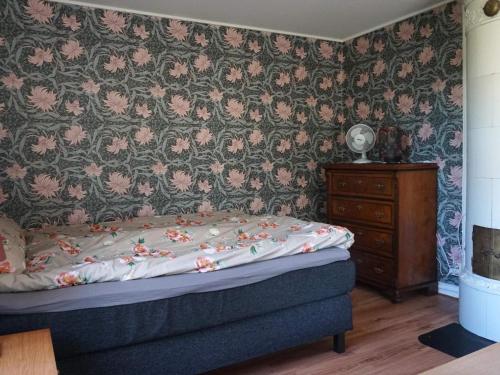 龙讷比Holiday home RONNEBY IX的一间卧室配有一张床和一张带花卉壁纸的墙壁