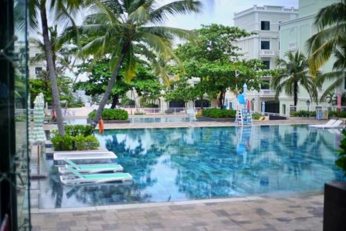 富国Elene Phu Quoc的一座游泳池,里面摆放着椅子和棕榈树
